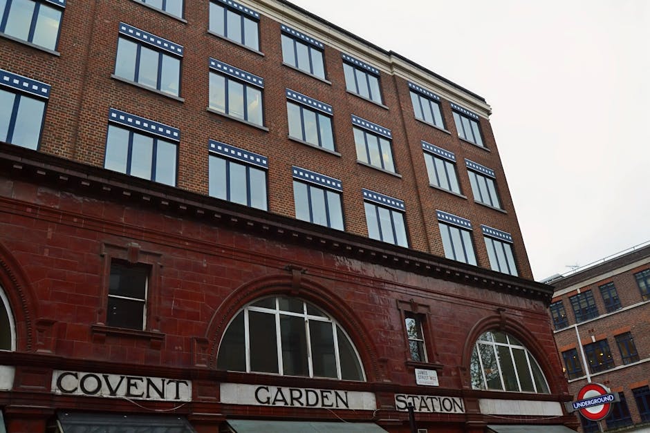 A paved urban garden terrace in Covent Garden features multiple rectangular wooden planters filled with a variety of plants, including succulents, shrubs, and flowering species. The planters are arran